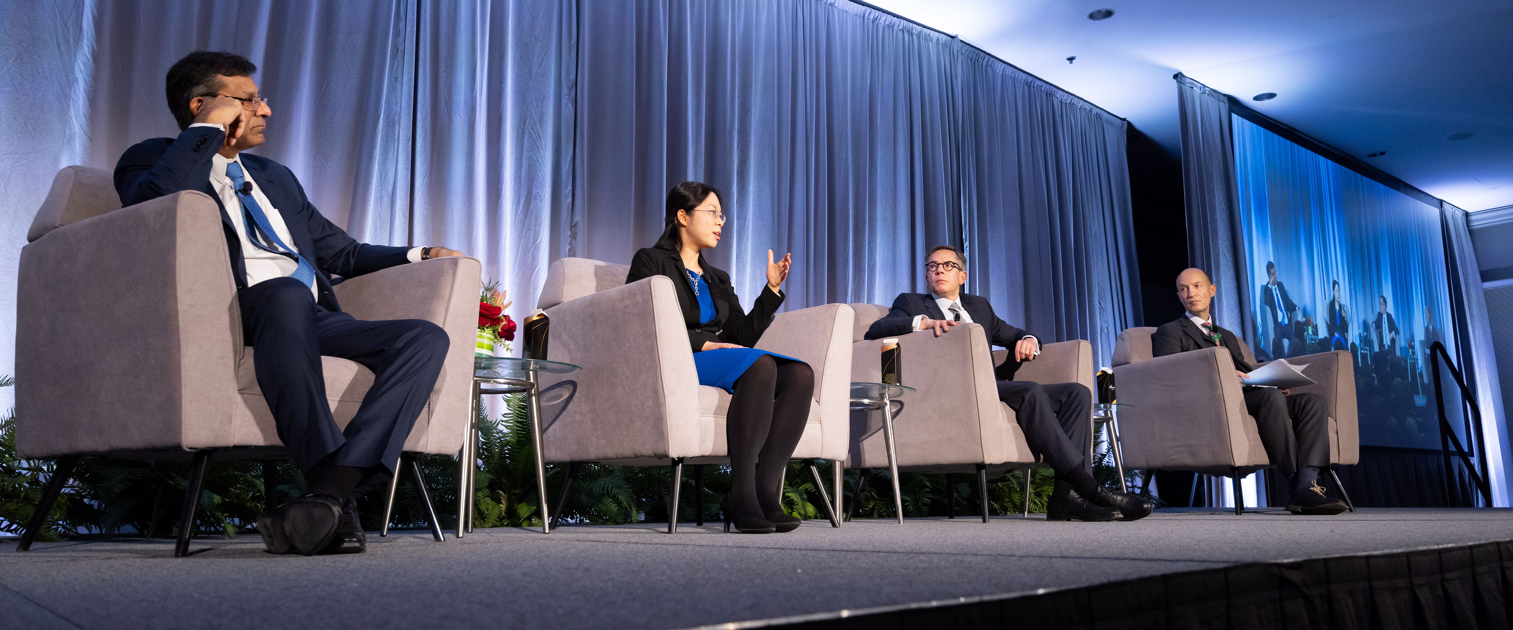 Booth professors Raghuram Rajan, Yueran Ma, and Randy Kroszner sitting on stage speaking to Hal Weitzman.
