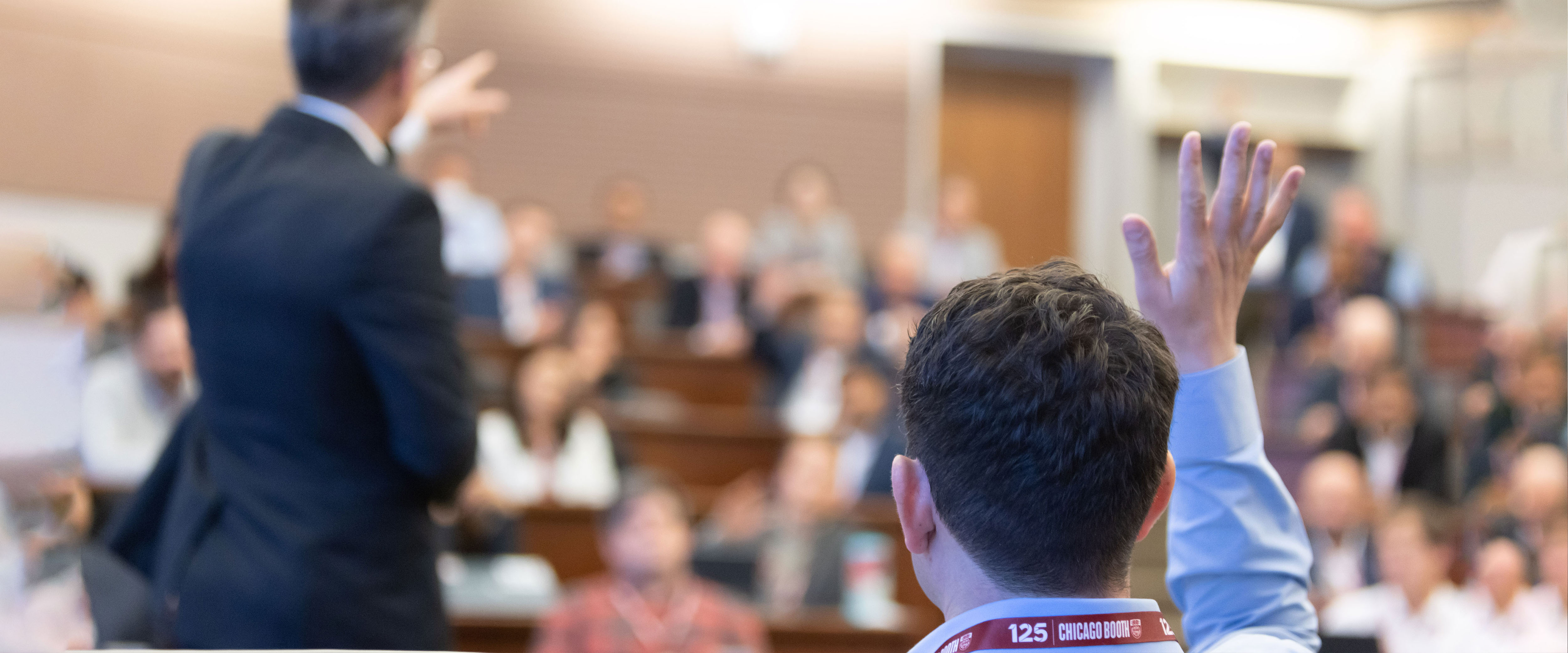 Chicago Booth master's student raising his hand in a lecture