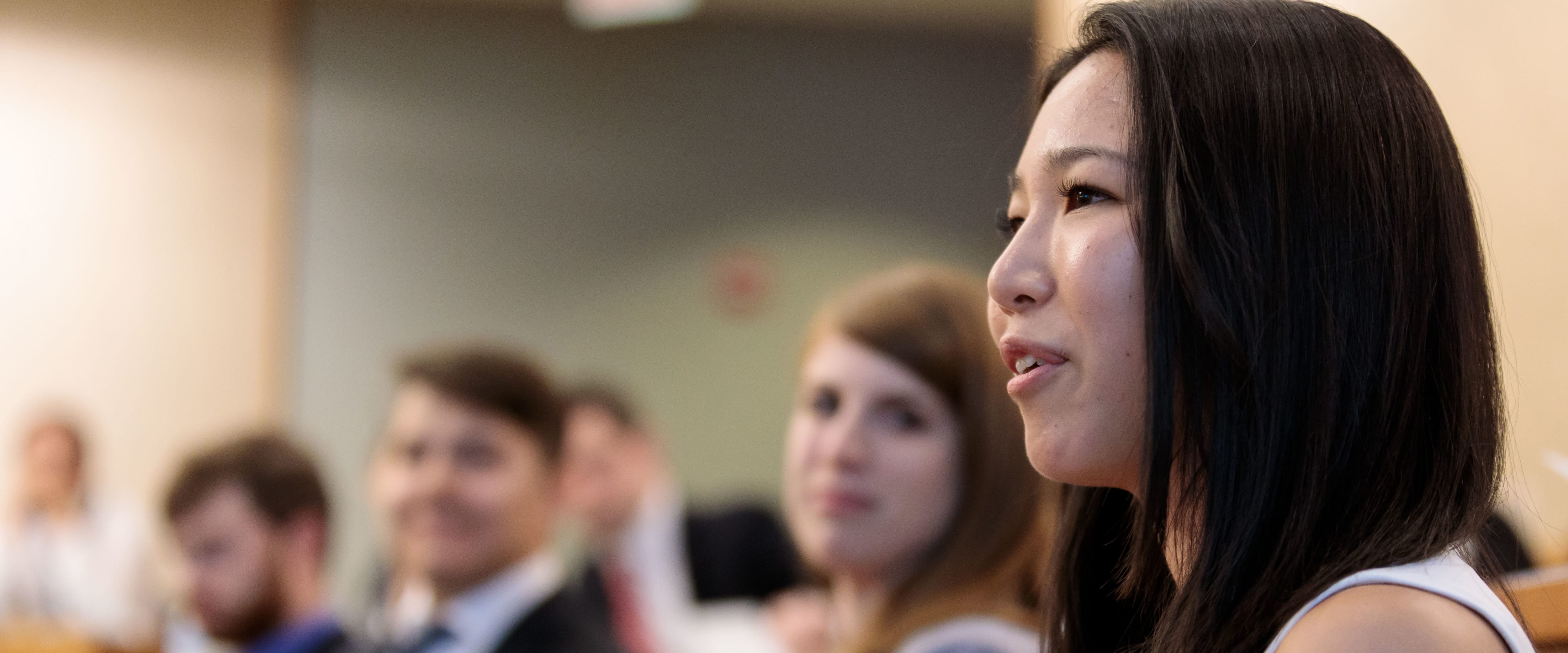 Female student seated, addressing the classroom