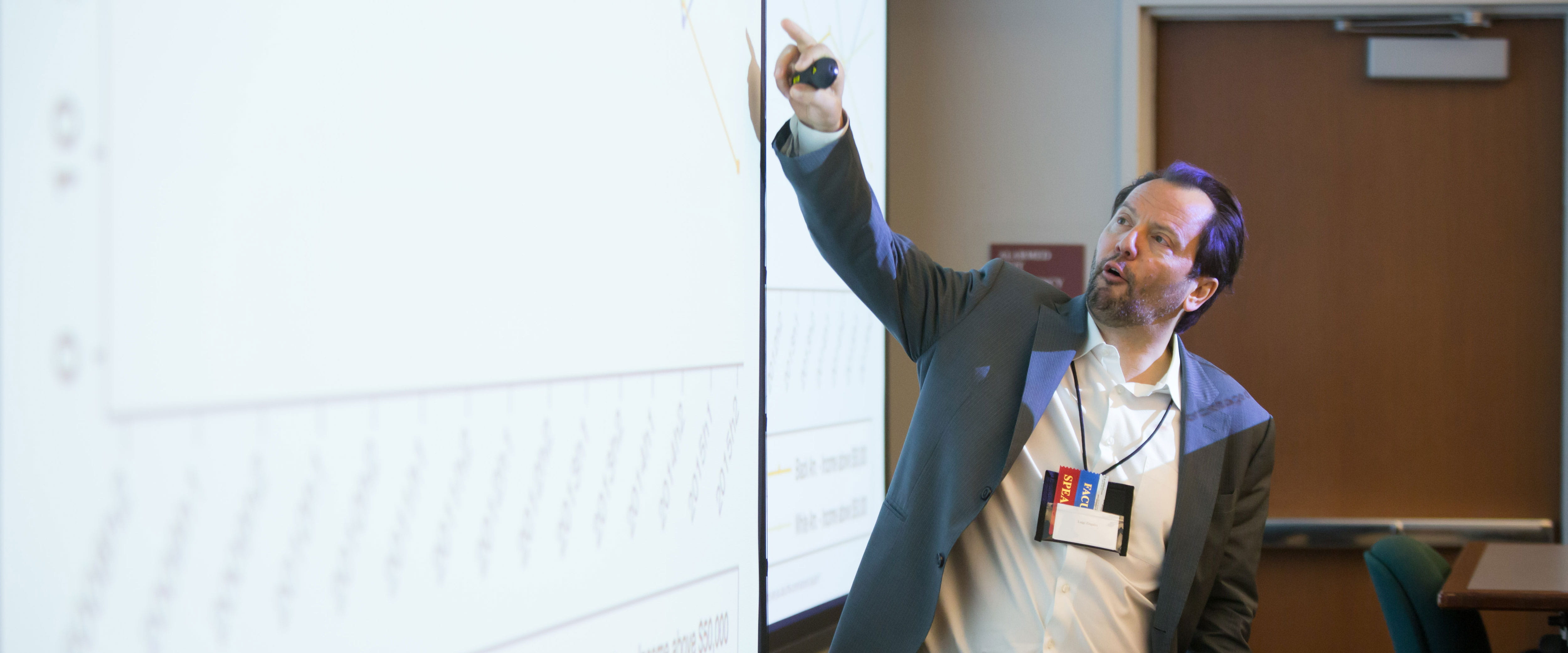 Professor Luigi Zingales pointing to a projection screen while teaching a class