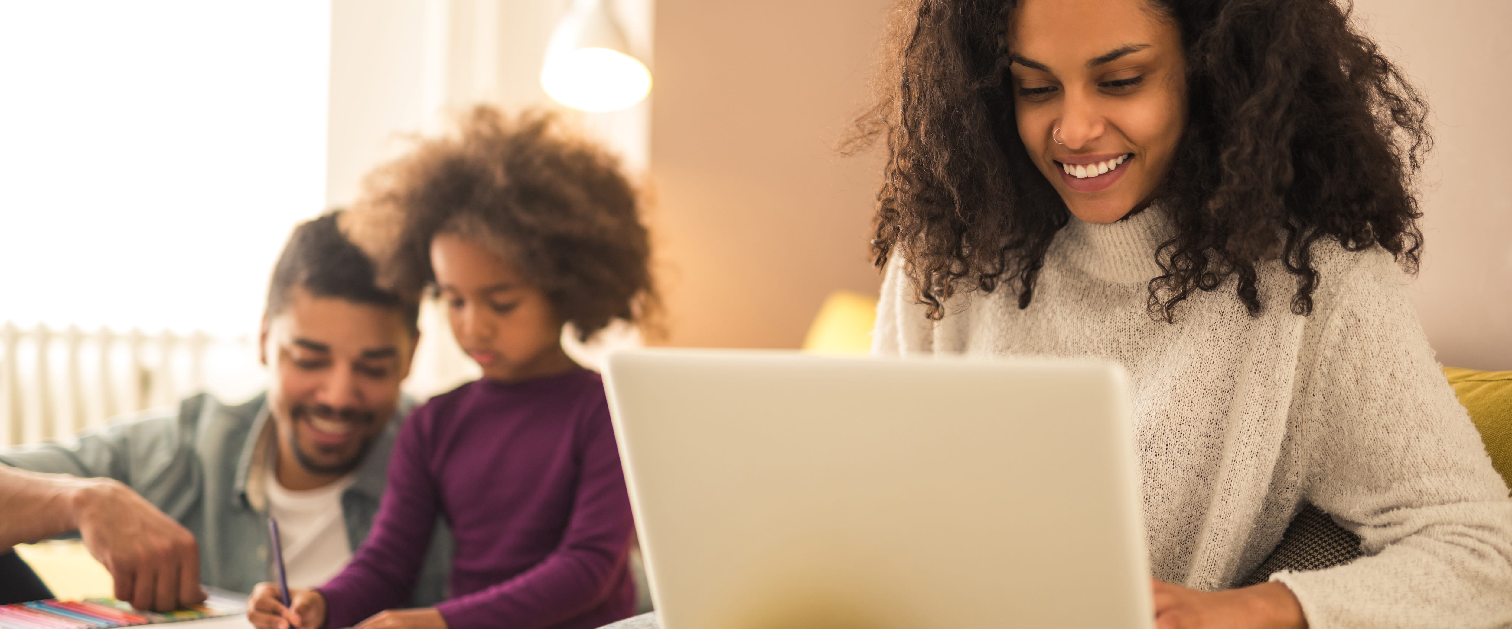 woman-using-laptop-family-in-background.jpg