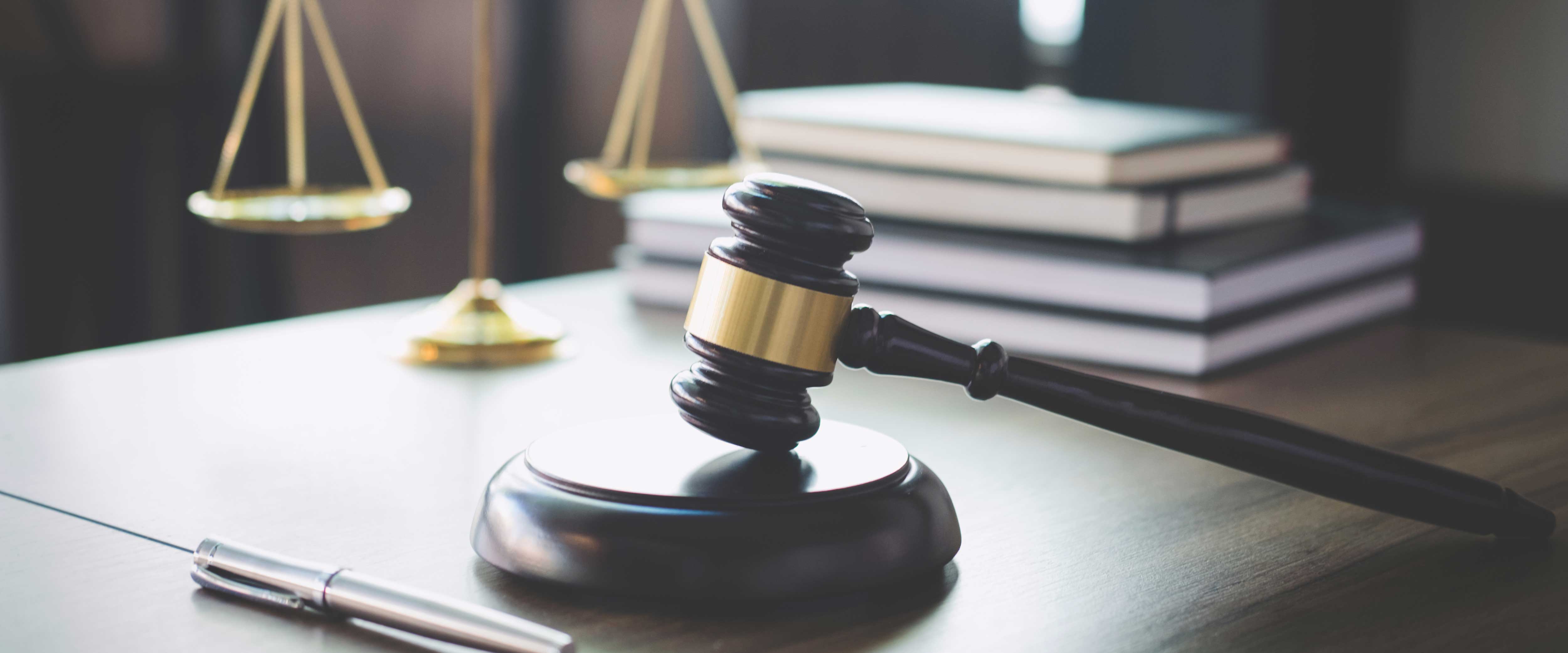 Gavel with scales of justice behind it on a desk