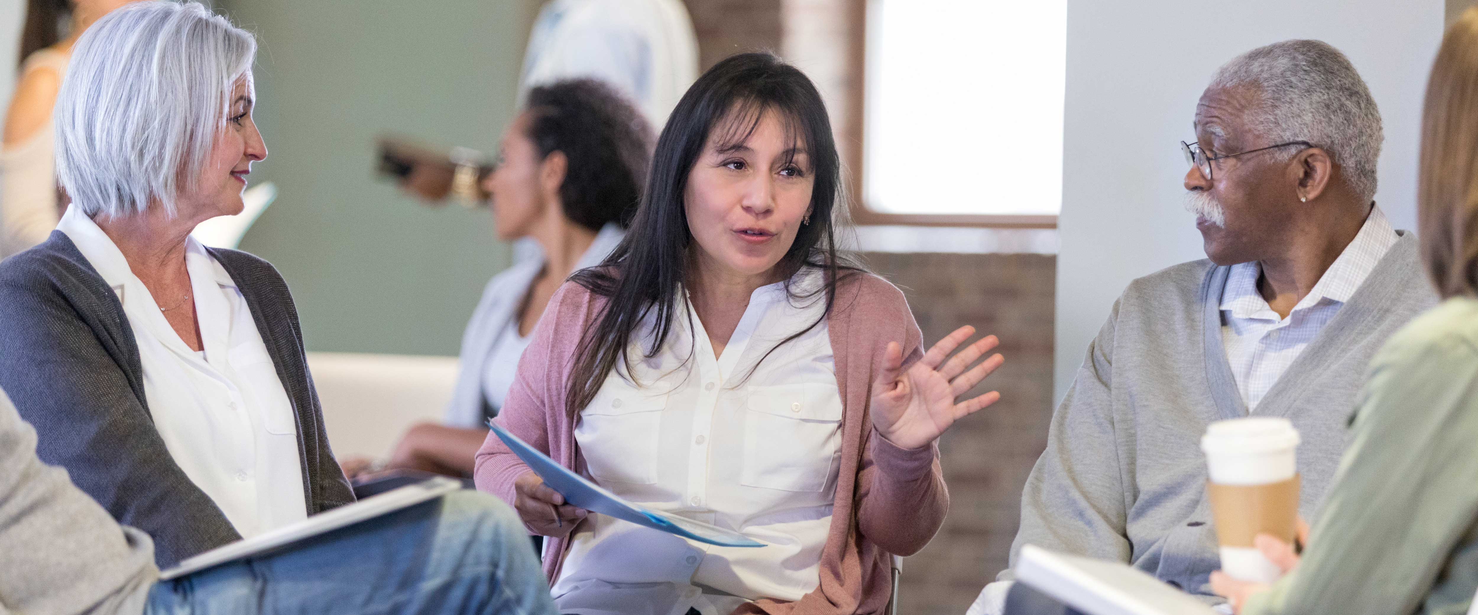 A woman leading a group discussion of elderly people