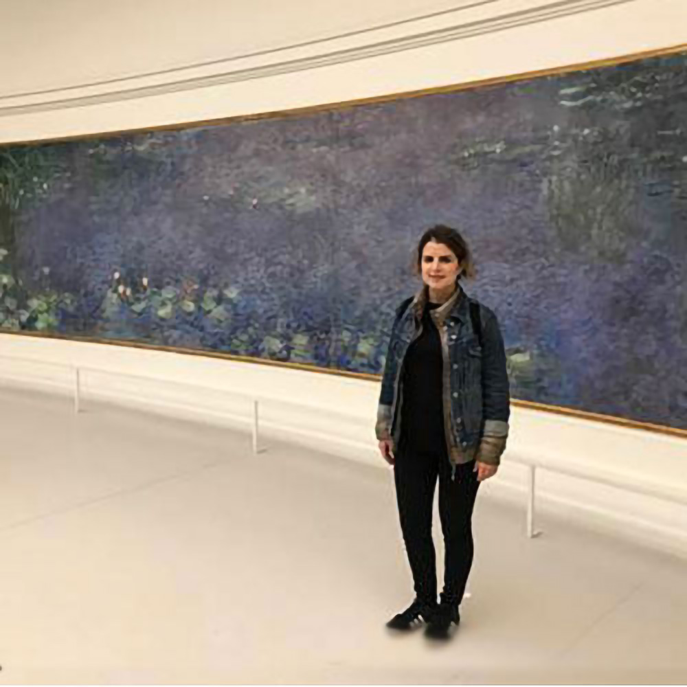 Photo of Yuli Almozlino in front of a mural