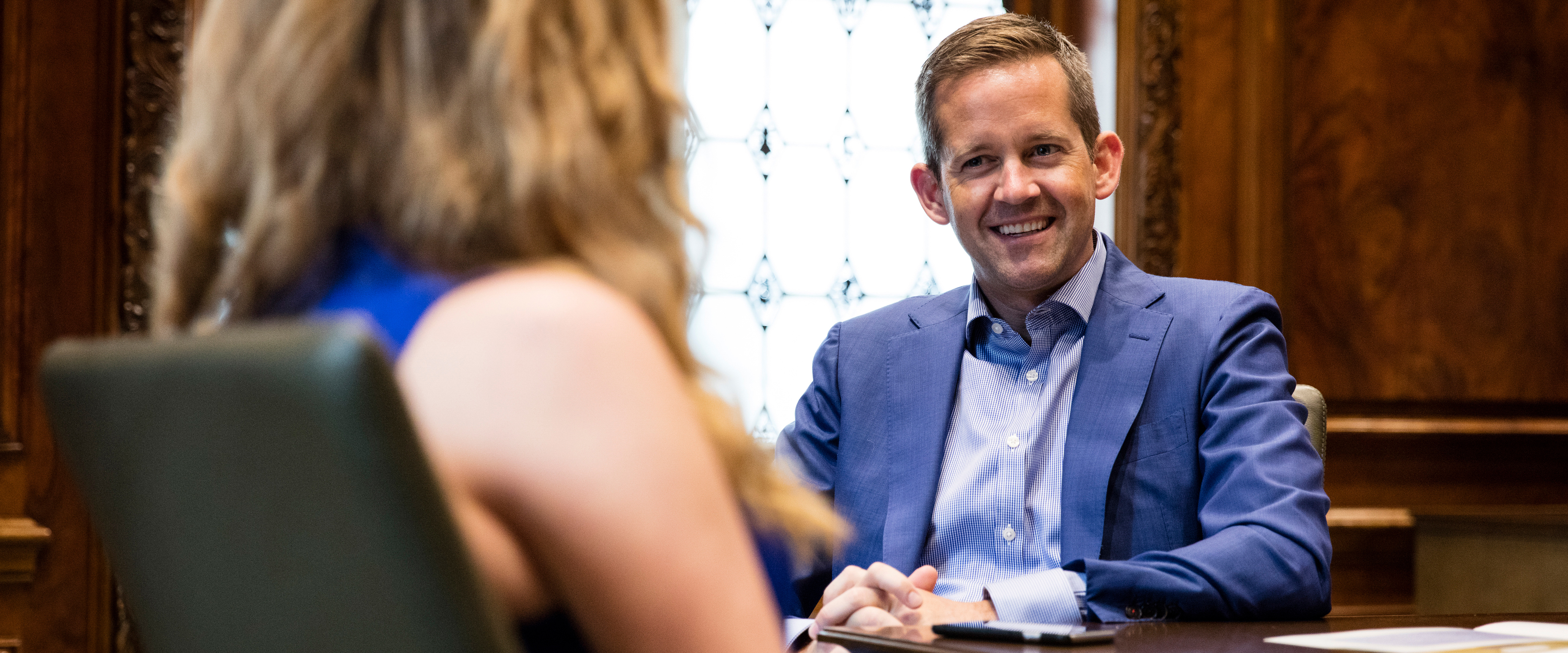 Male professional in conversation with student, sitting at desk