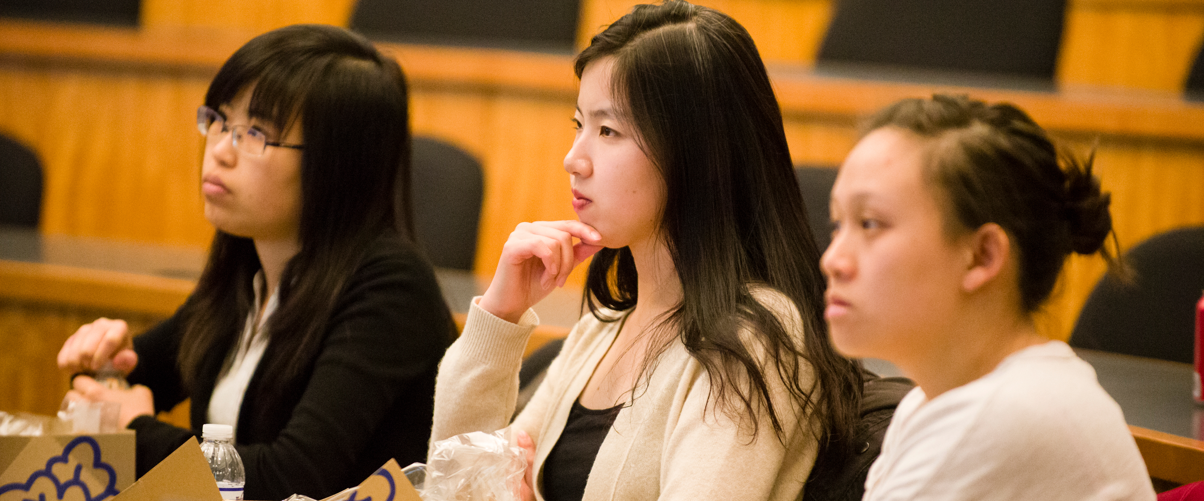 Three Asian women sitting in class listening to a lecture