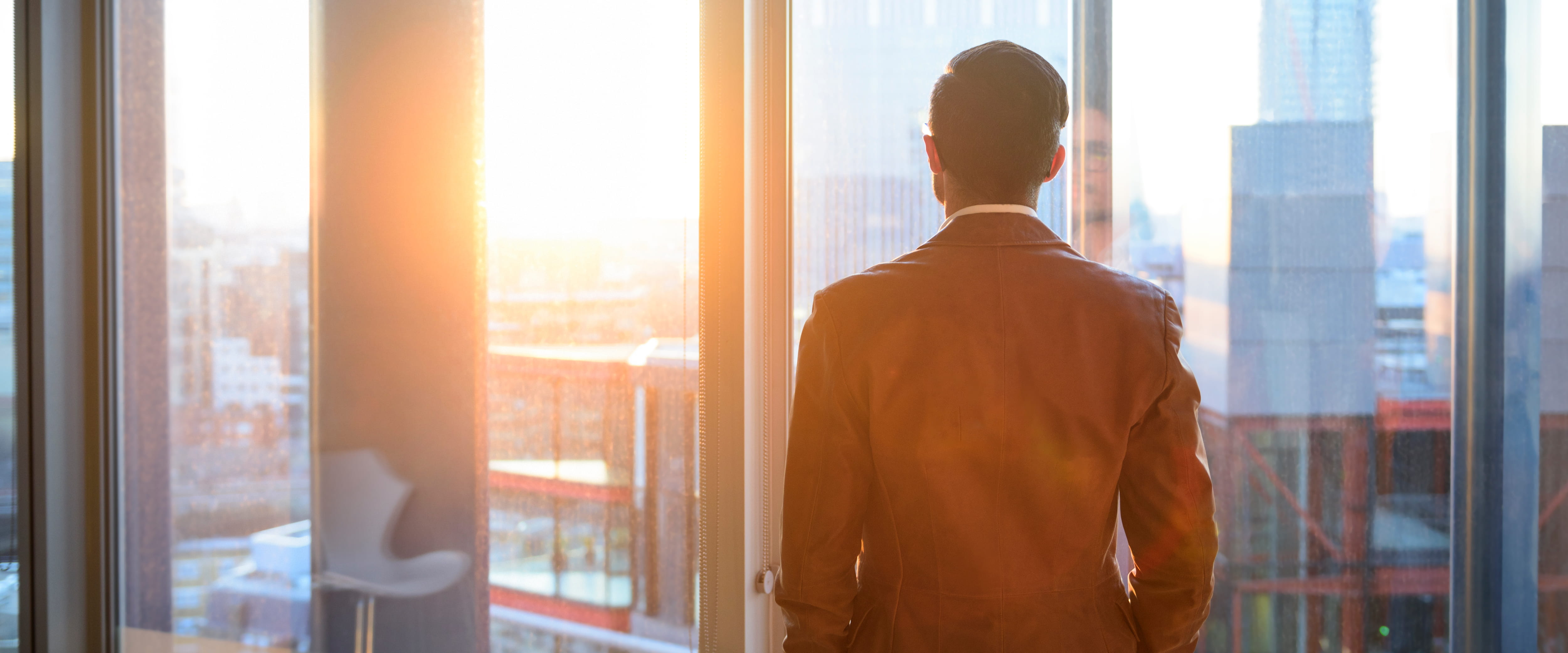 Man looking out of a window at the city