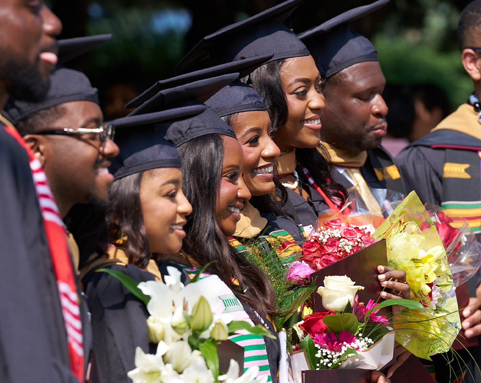 A row of graduates smile.